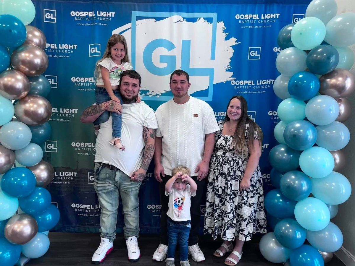 A family smiling in front of the Gospel Light banner